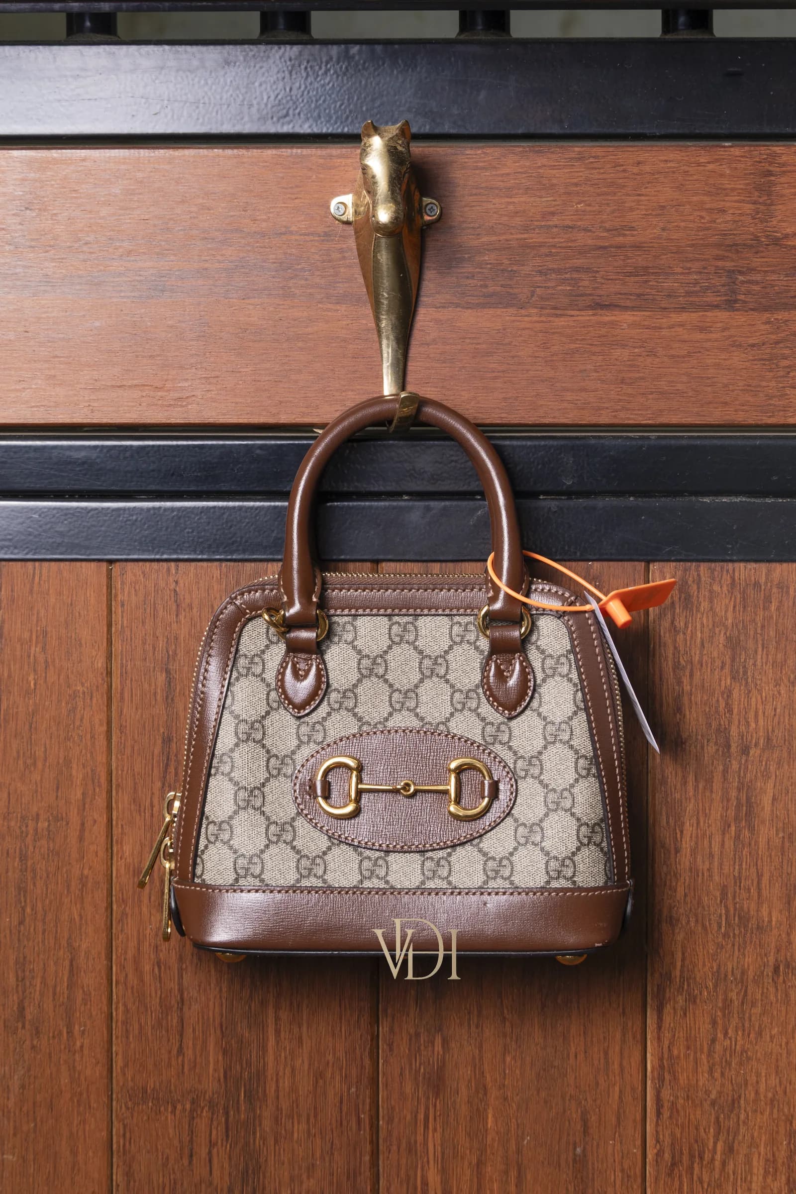 Gucci 1955 Horsebit vintage appesa a una porta in teak con cavallo in ottone, ambiente d'archivio